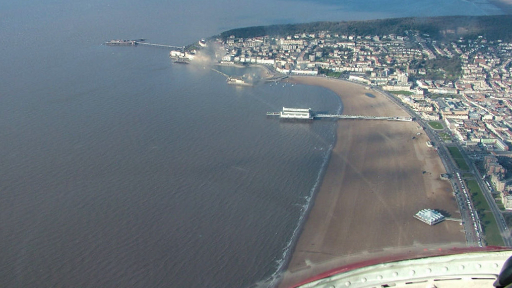 Aerial view over Weston-super-Mare showing the town, sea, beach and two pierss